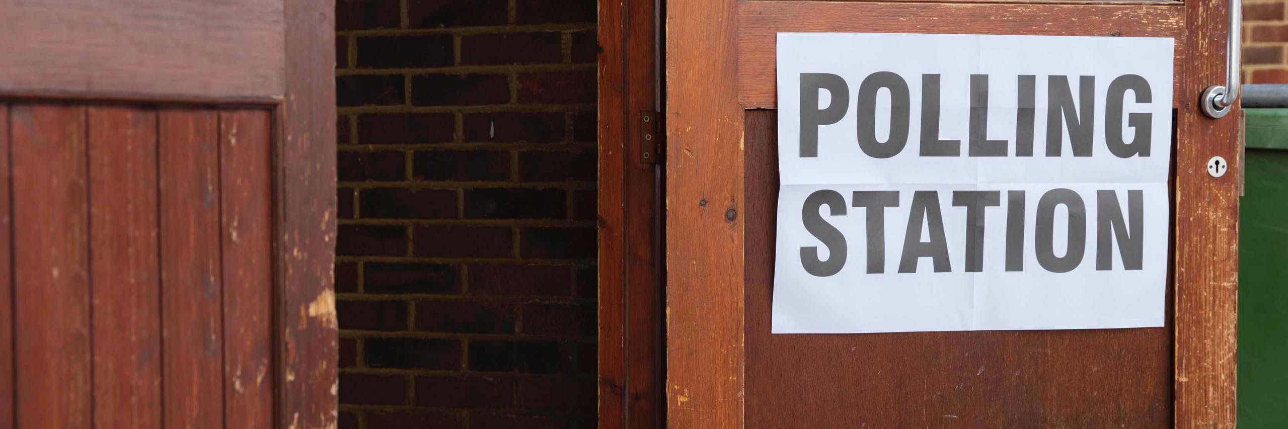 Polling Station poster stuck on an open wooden door at a polling station