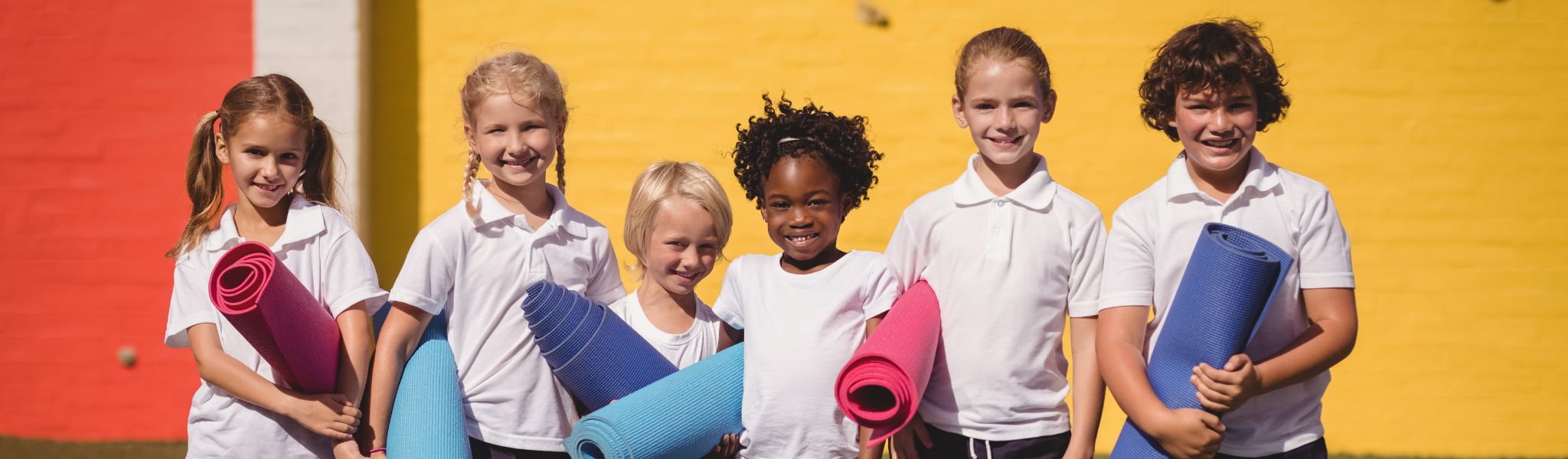 An image of a group of children in a line with yoga mats
