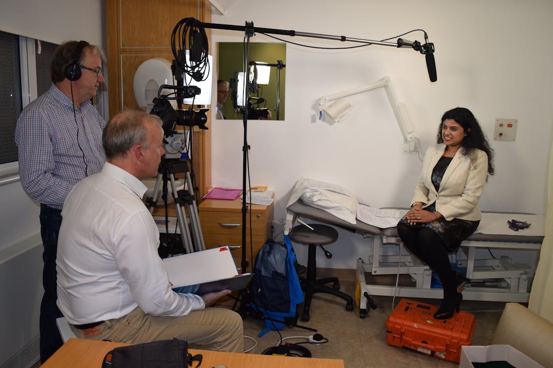 Doctor being filmed and recorded by film crew with microphone