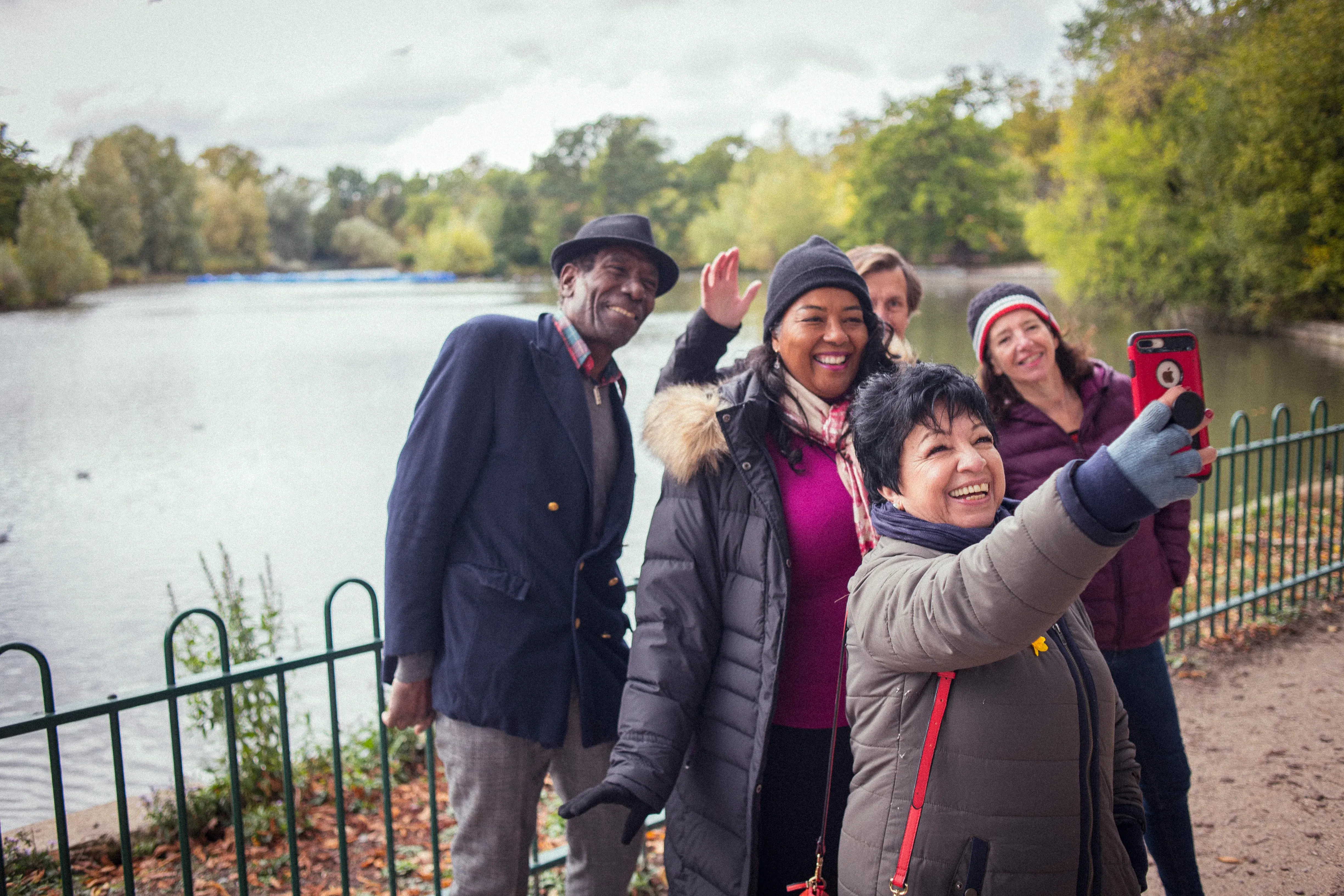 5 people are smiling and taking a selfie together by a lake