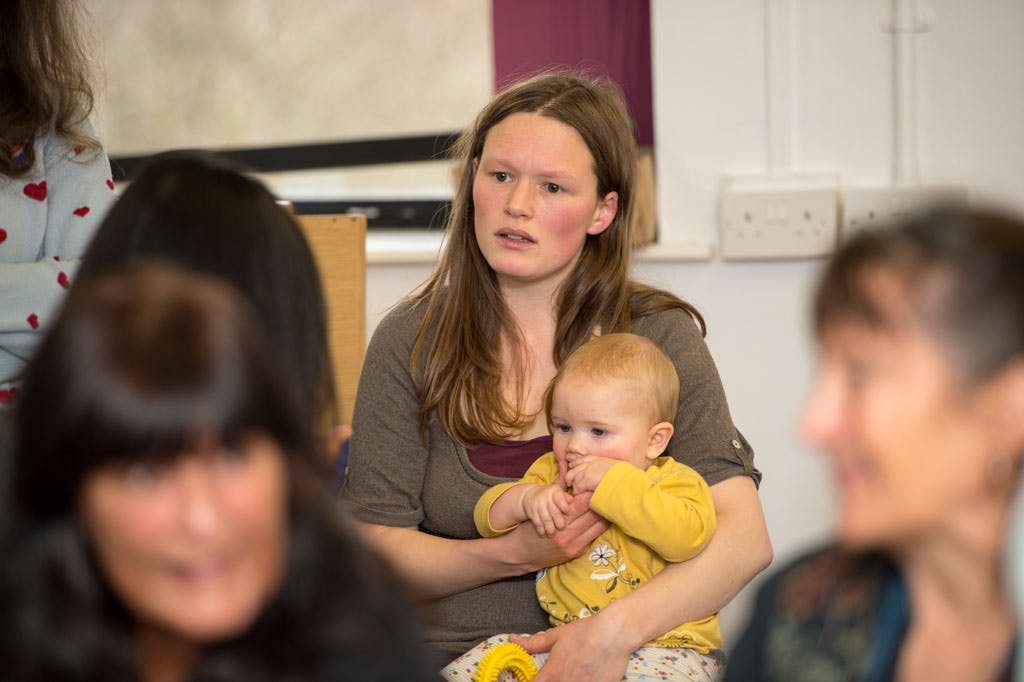Mum sat down holding baby at group event