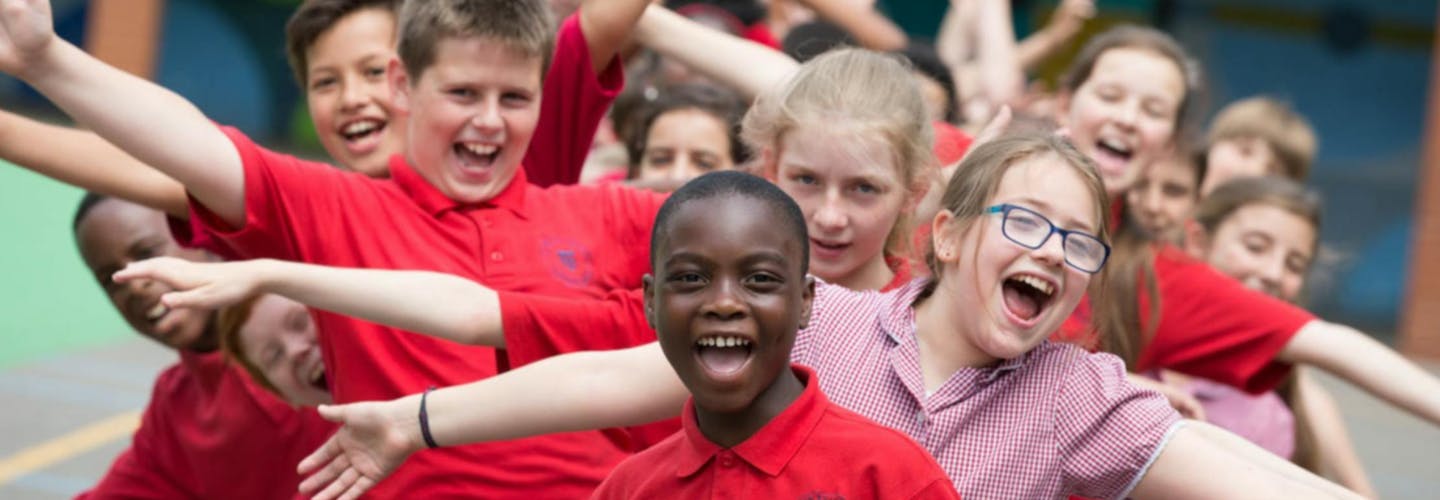 Group of young children dressed in school uniform cheering happily