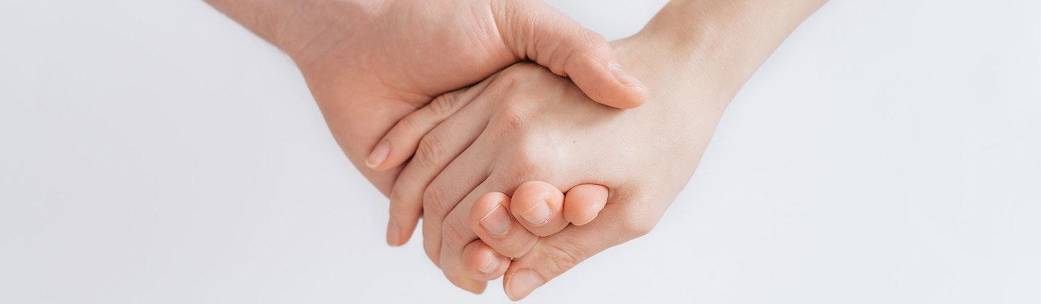 An image of 2 adults holding hands