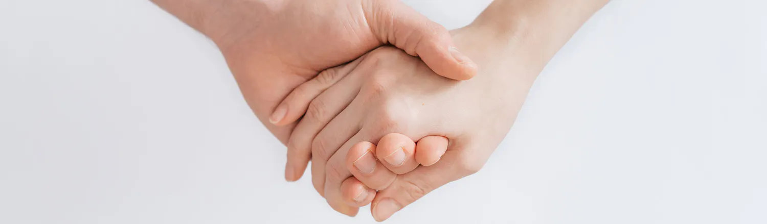 An image of 2 adults holding hands