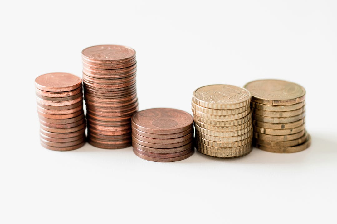 Close up of a hand placing a coin on a small stack of coins